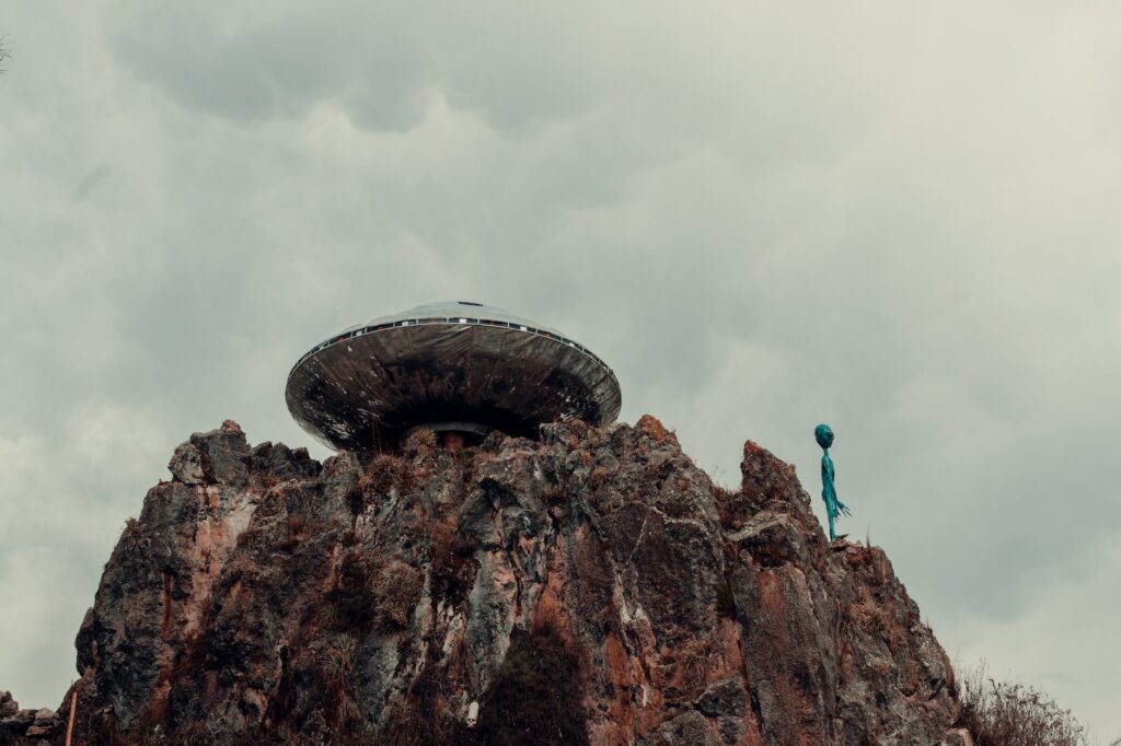 ufo and an alien on a rock formation